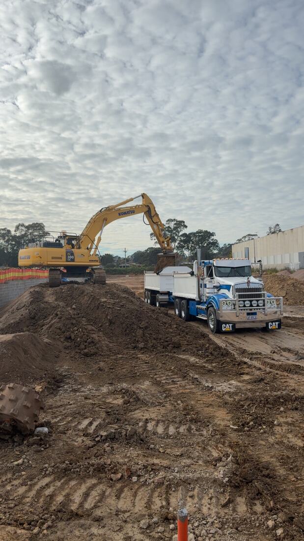 Excavator loading a tipper with spoil on a residential cut