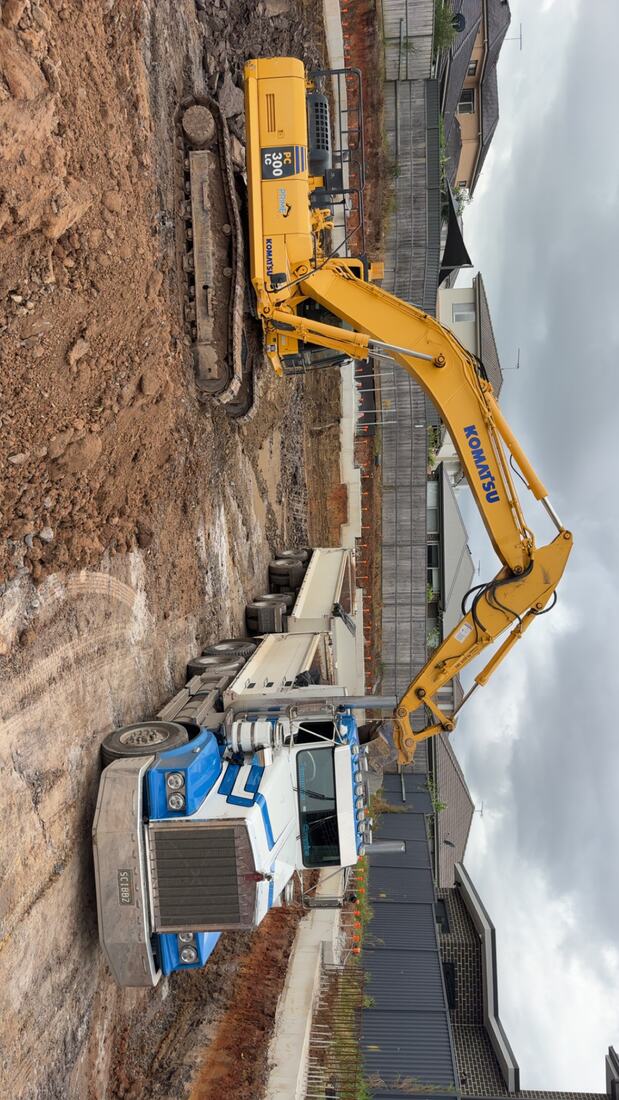 Long-reach excavator working alongside a concrete retaining wall