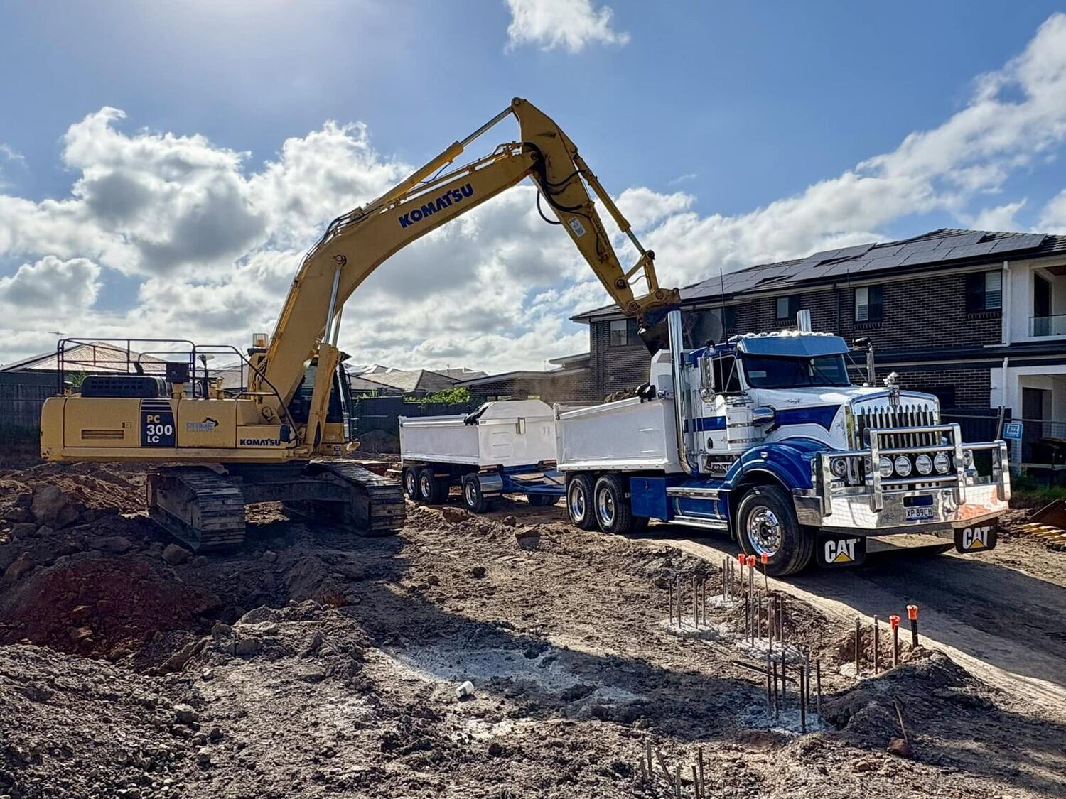 Komatsu PC300 excavator loading a Kenworth truck and dog