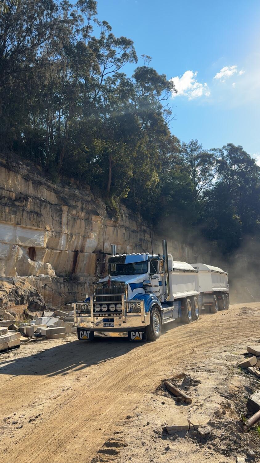 Kenworth truck and dog hauling spoil along a dusty site road